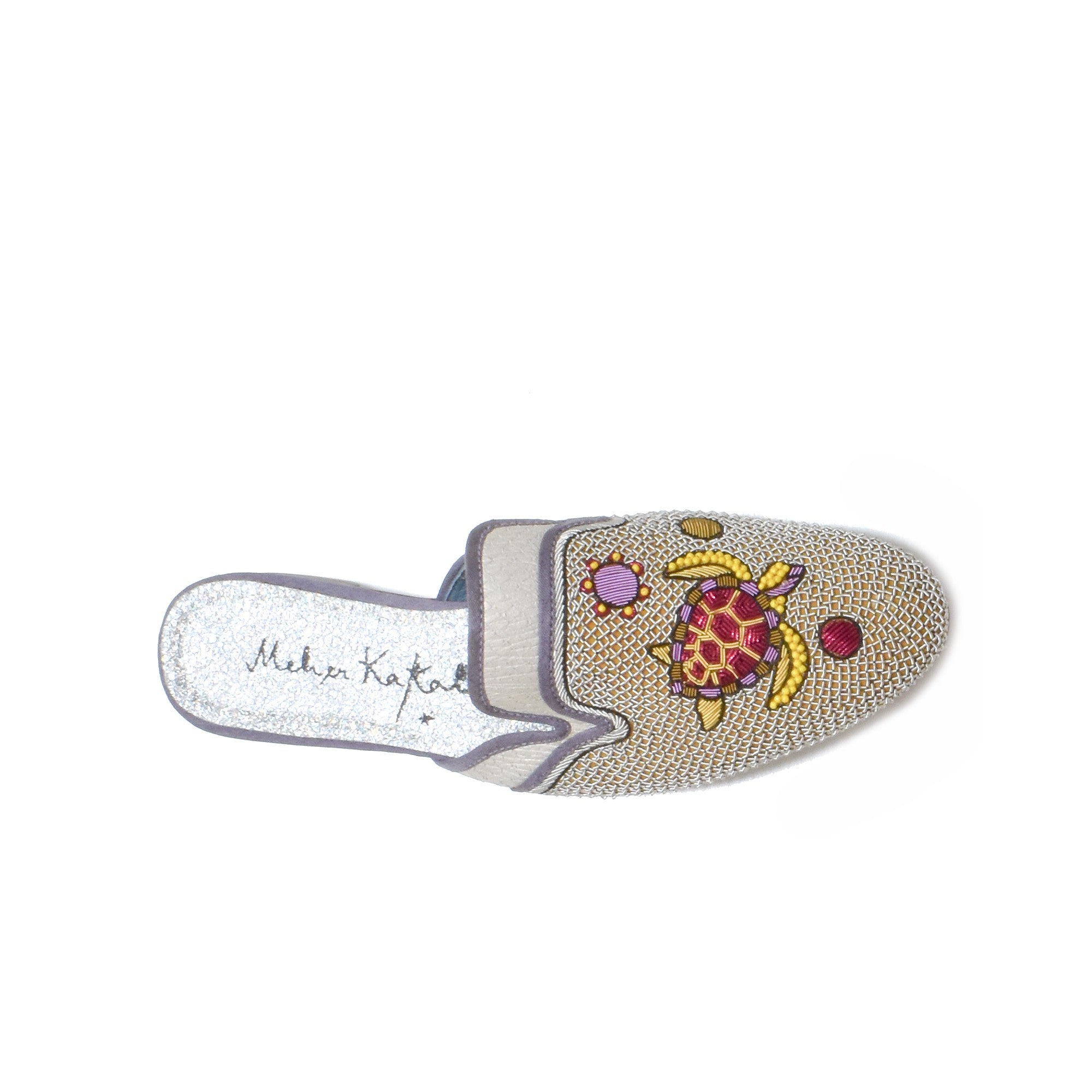Handcrafted leather slippers with intricate turtle embroidery, designed for a chic, sustainable summer look.