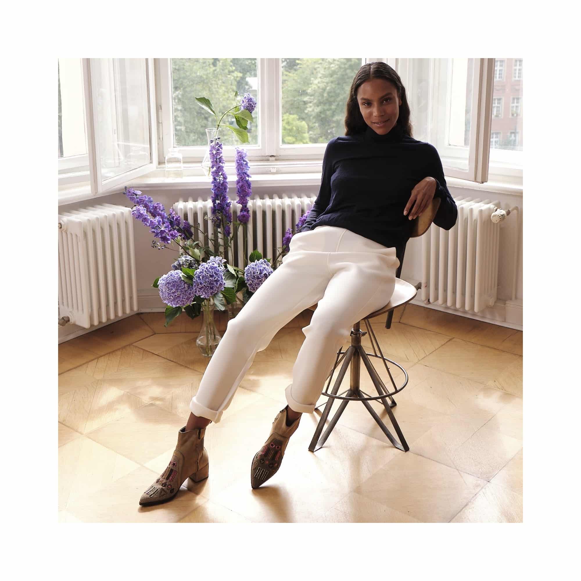Model wearing suede embroidered ankle boots in a bright interior room